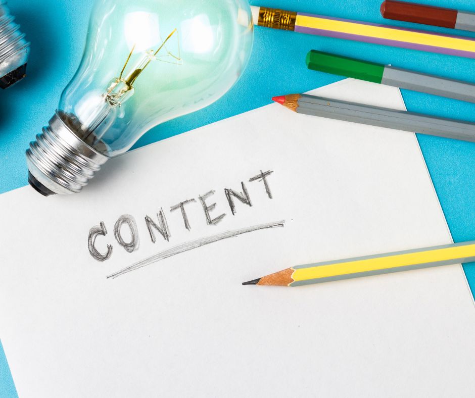 Glühbirne, bunte Bleistifte und ein Blatt Papier mit dem handgeschriebenen Wort „CONTENT“, symbolisch für Ideenfindung und kreatives Arbeiten.