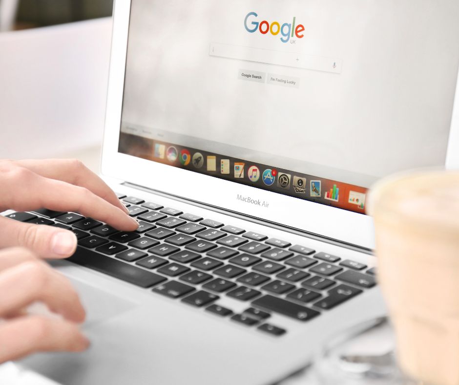 Person tippt auf einem MacBook Air, auf dem Bildschirm ist die Startseite der Suchmaschine Google geöffnet.