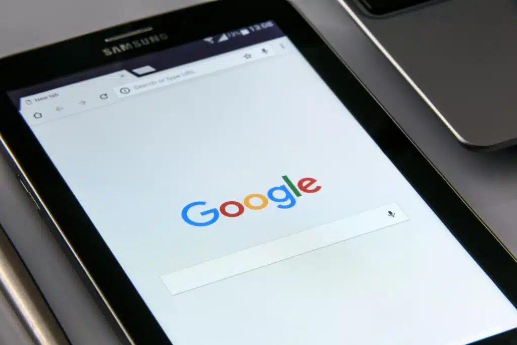 Auf dem Tisch liegt ein Tablet, auf welchem die Startseite von Google geöffnet ist.